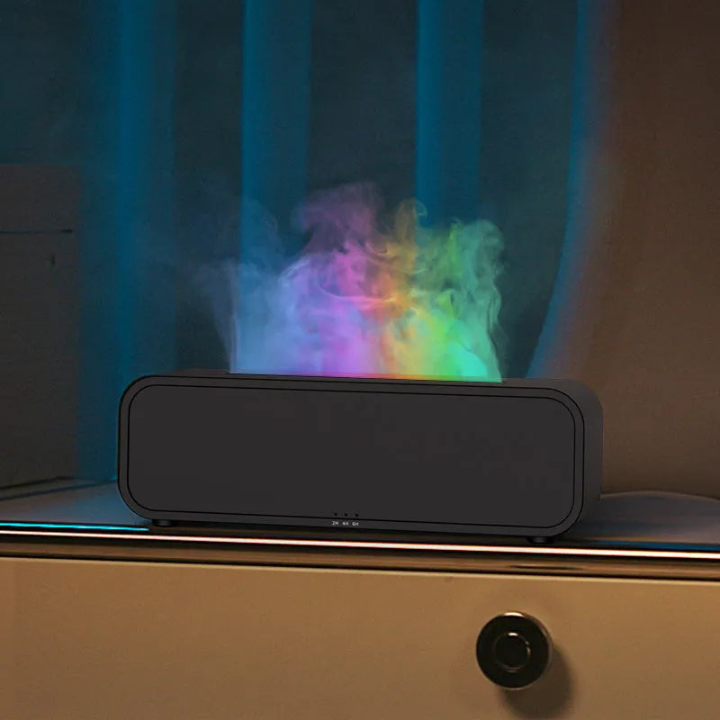 Black and white USB aroma diffuser with remote control on a desk, showing colour-changing LED lights.