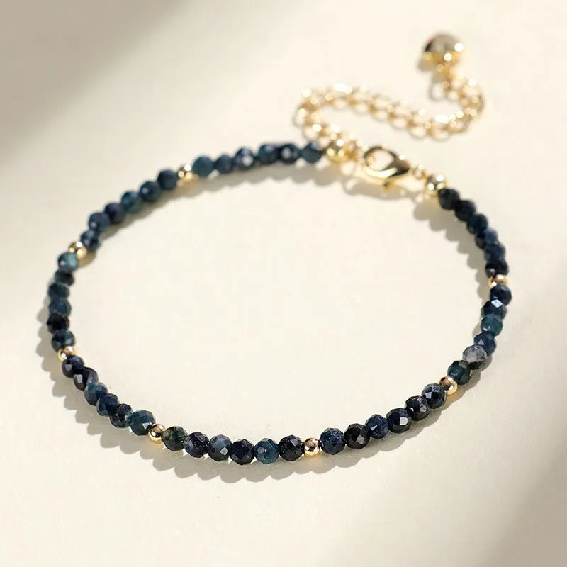 Close-up of a women's blue tourmaline beaded bracelet with 3mm beads and spacer sections.