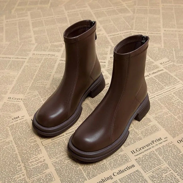 Black women's flat-heel ankle boots with a round toe and back zipper on a white background