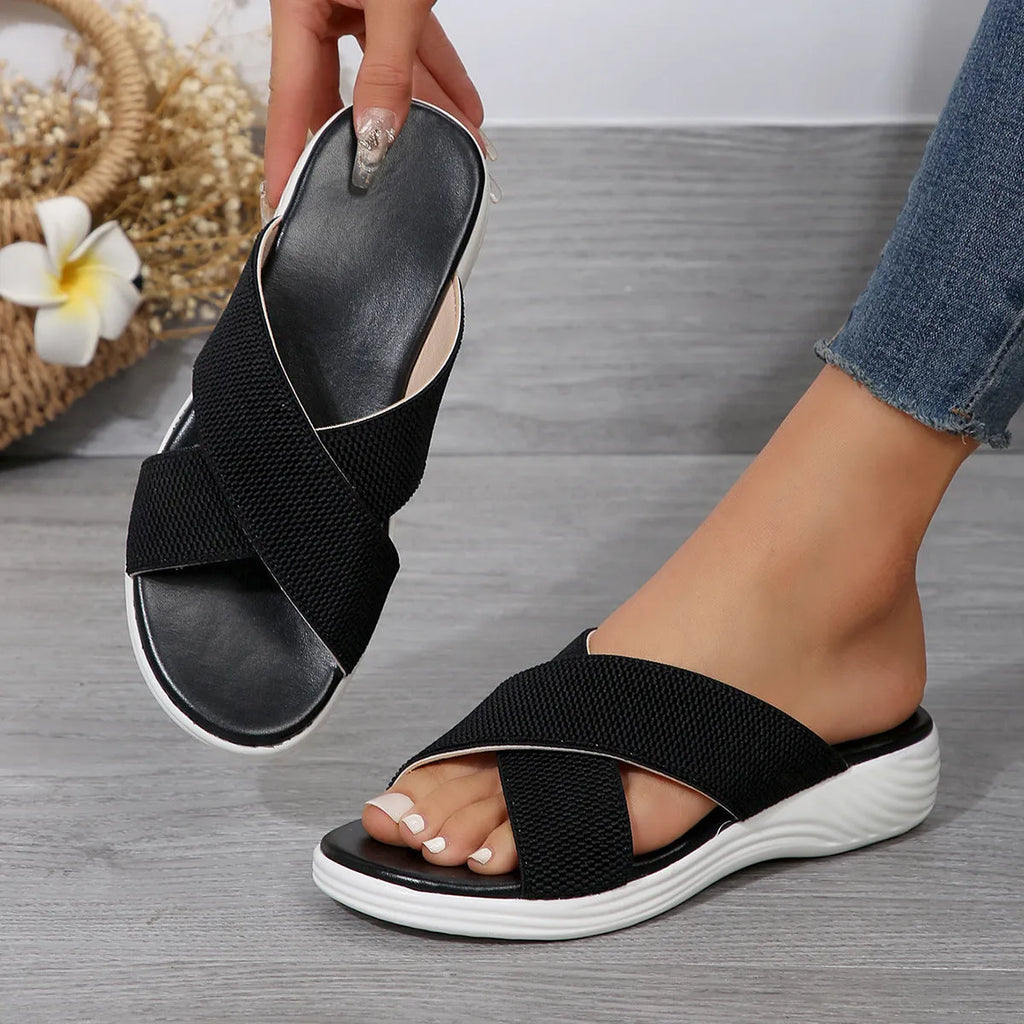 Women's black wedge slippers with peep-toe design and cross-strap PVC upper on thick rubber sole
