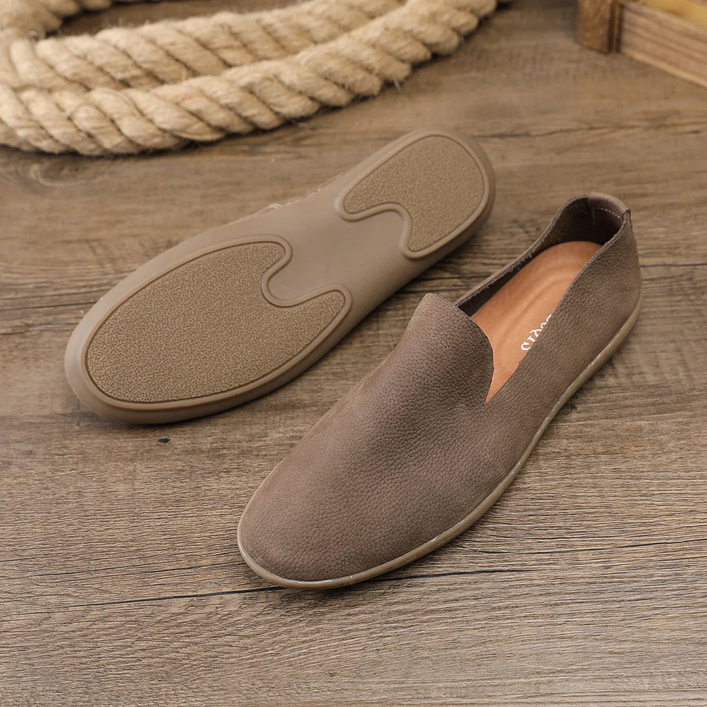 Handmade grey men's low-top leather shoes with a flat wedge rubber sole on a plain background.
