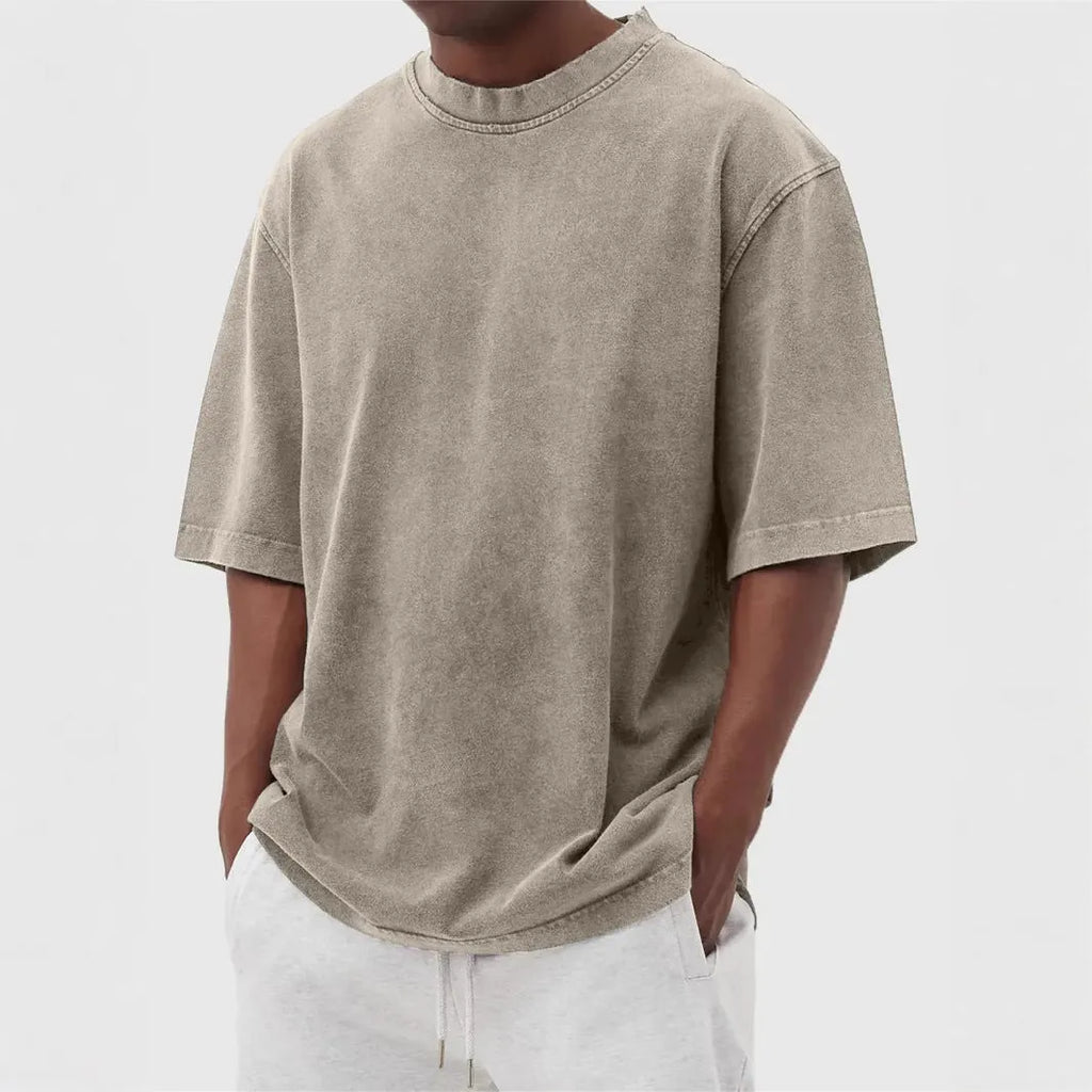 Man wearing a loose-fit, stone-washed distressed pullover T-shirt in a solid colour.