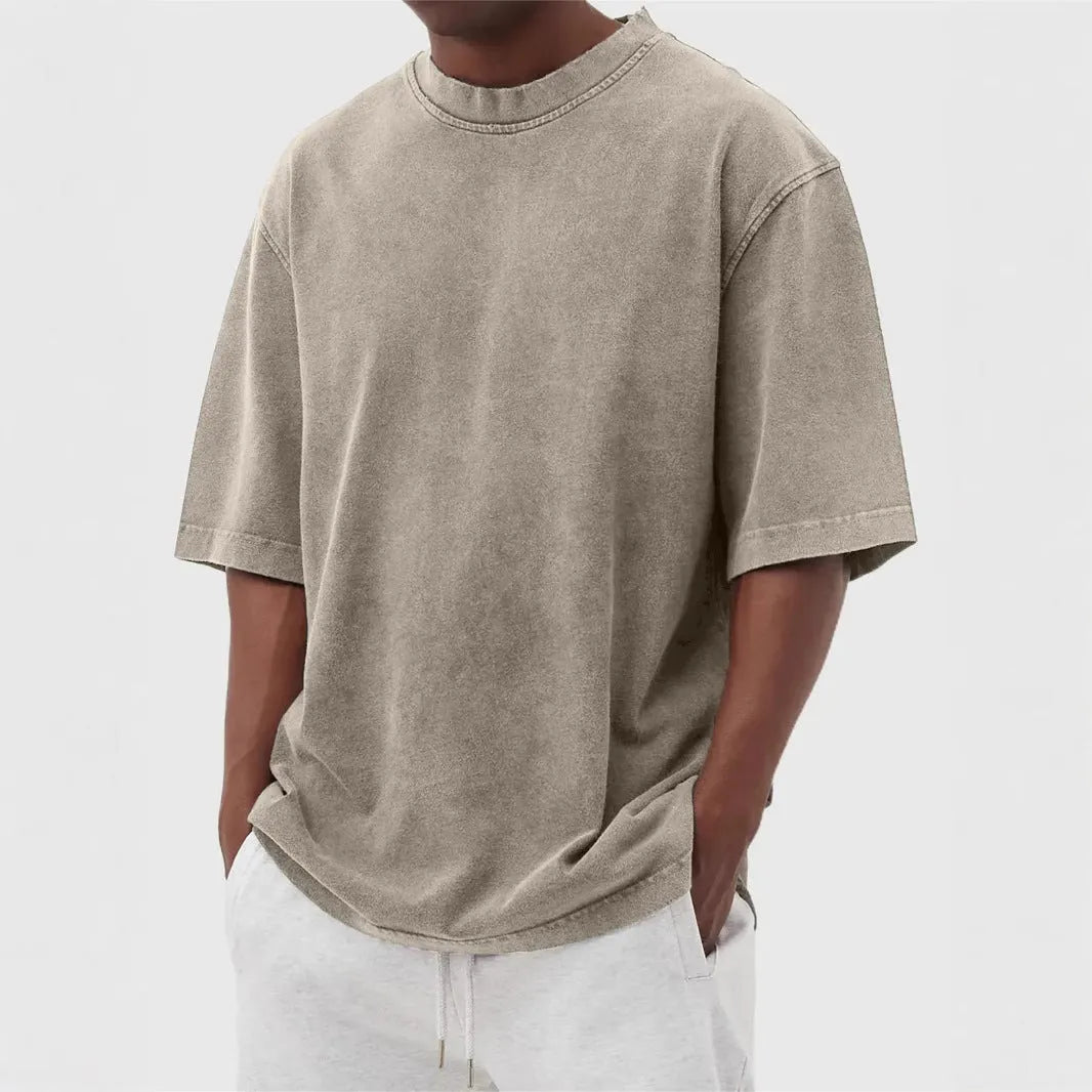 Man wearing a loose-fit, stone-washed distressed pullover T-shirt in a solid colour.