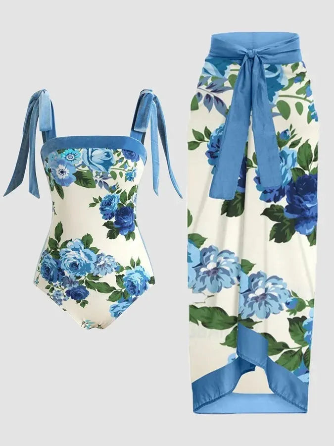 Women's floral print two-piece swimsuit with a blue chiffon skirt laid flat.