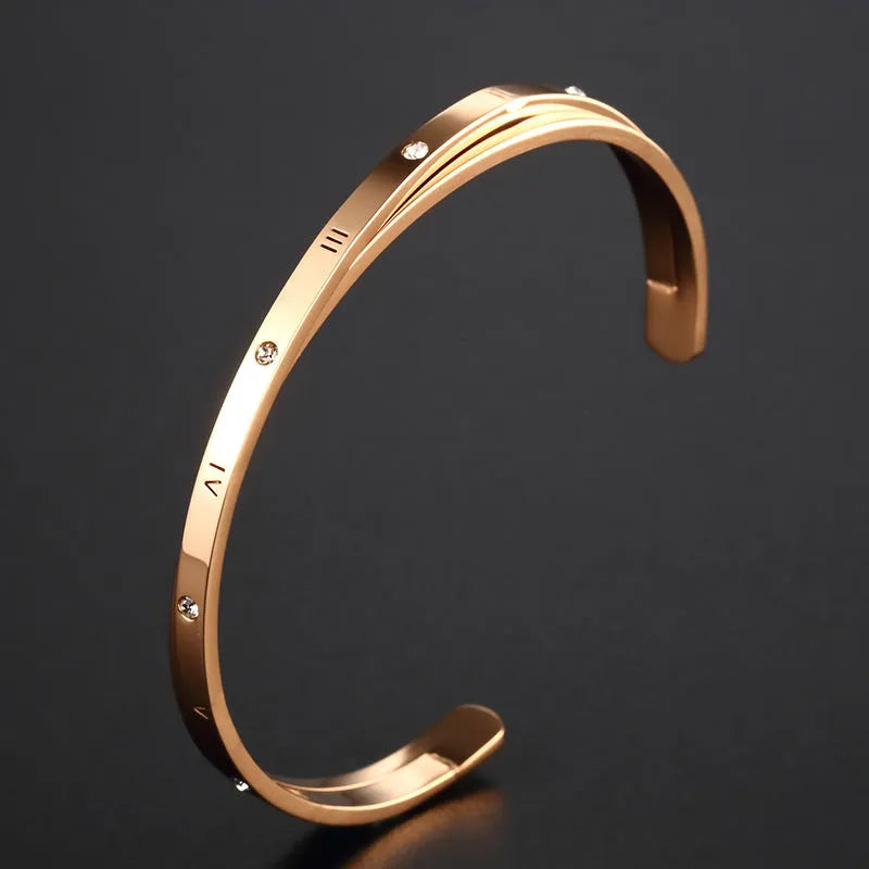 Open-ended stainless steel bracelet with zircon stones and love motif in electroplated gold finish