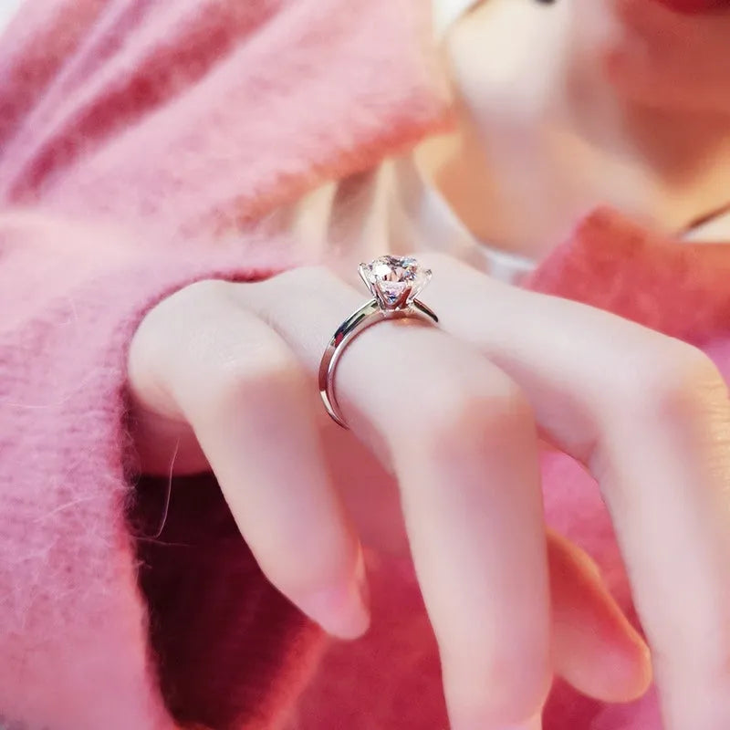 White gold plated geometric women's ring with a six-claw zircon setting, shown on a hand.