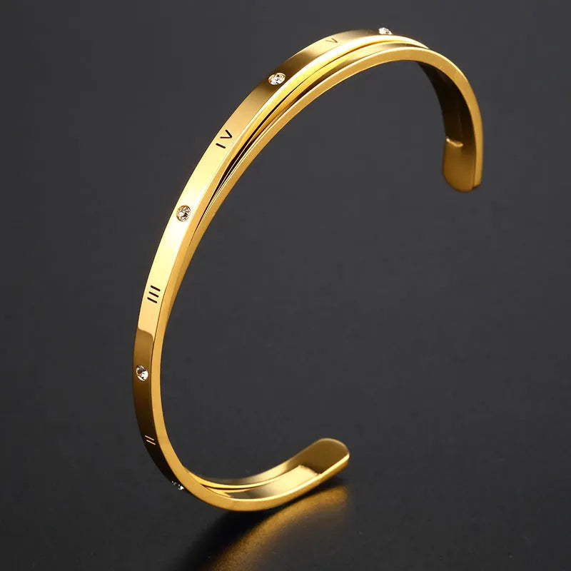 Open-ended stainless steel bracelet with zircon stones and love motif in electroplated gold finish