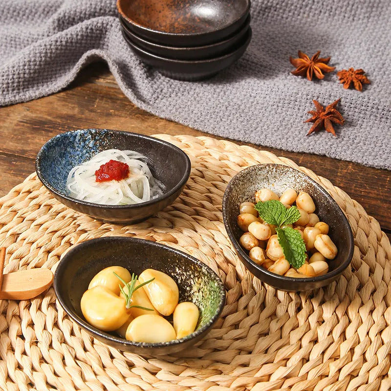 Oval Japanese ceramic dipping bowl with underglaze pattern on a wooden table.