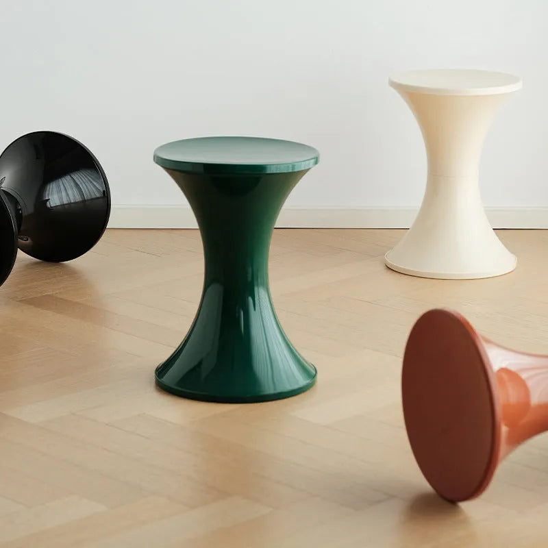 A plastic hourglass-shaped shoe changing stool in green colour on a wooden floor.