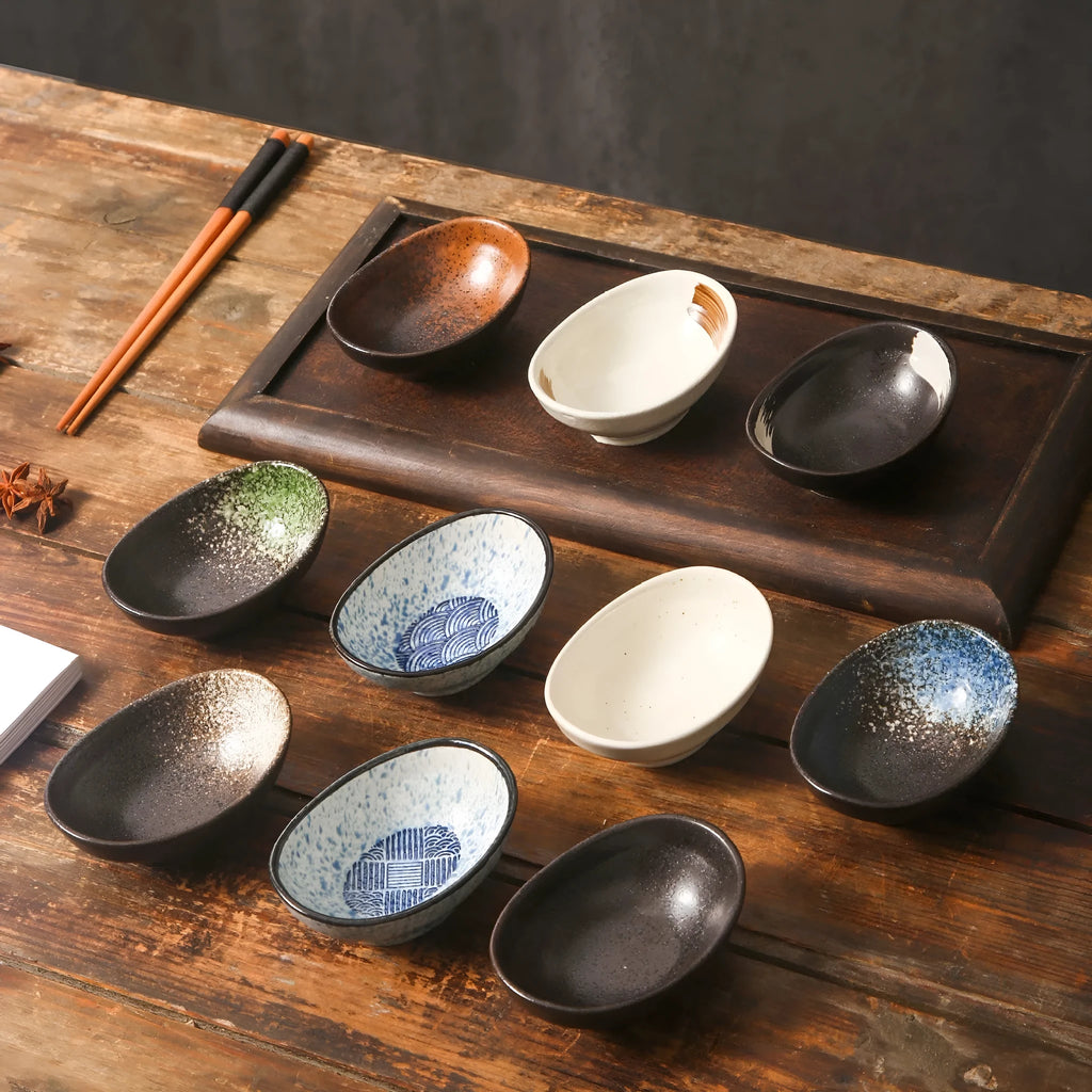Oval Japanese ceramic dipping bowl with underglaze pattern on a wooden table.