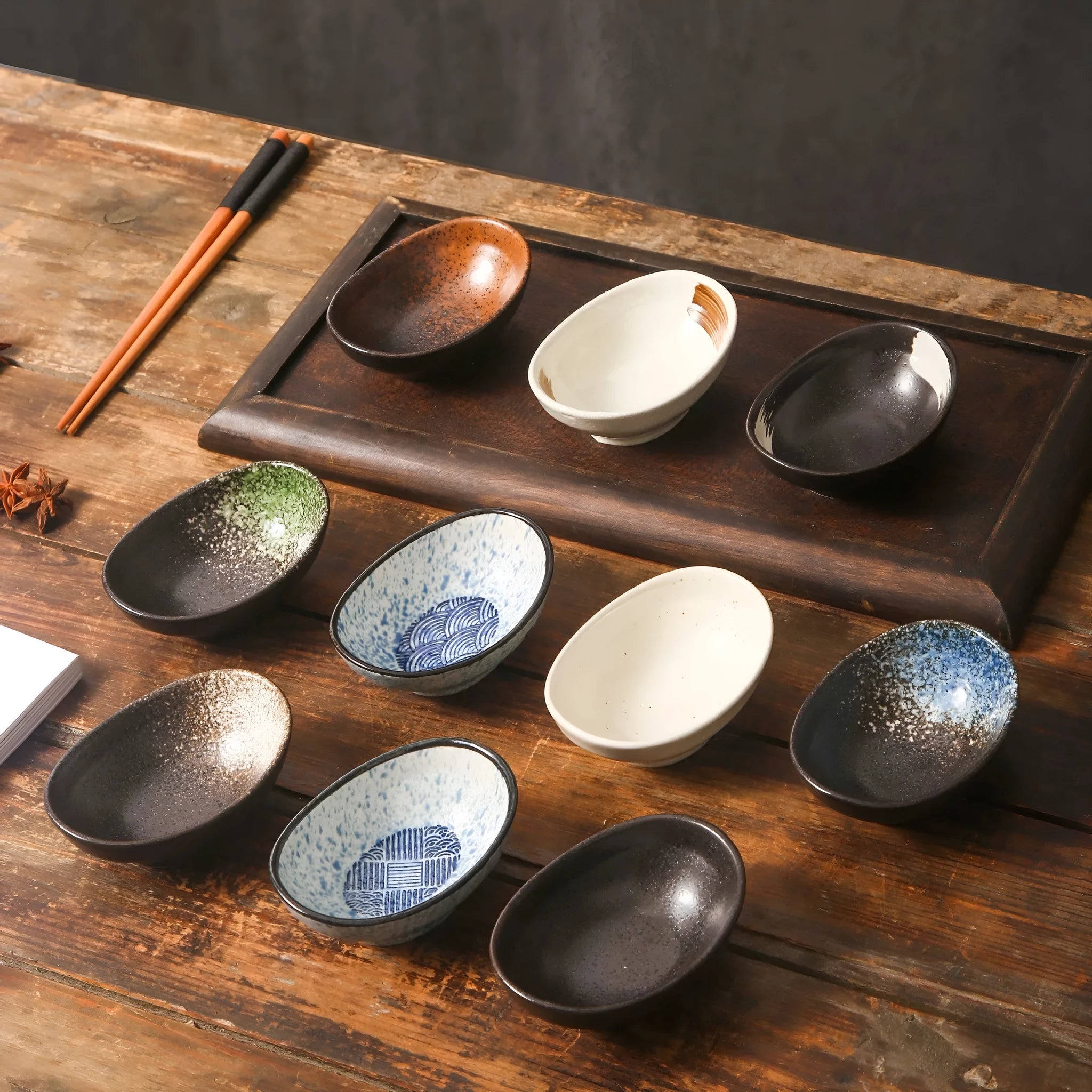 Oval Japanese ceramic dipping bowl with underglaze pattern on a wooden table.