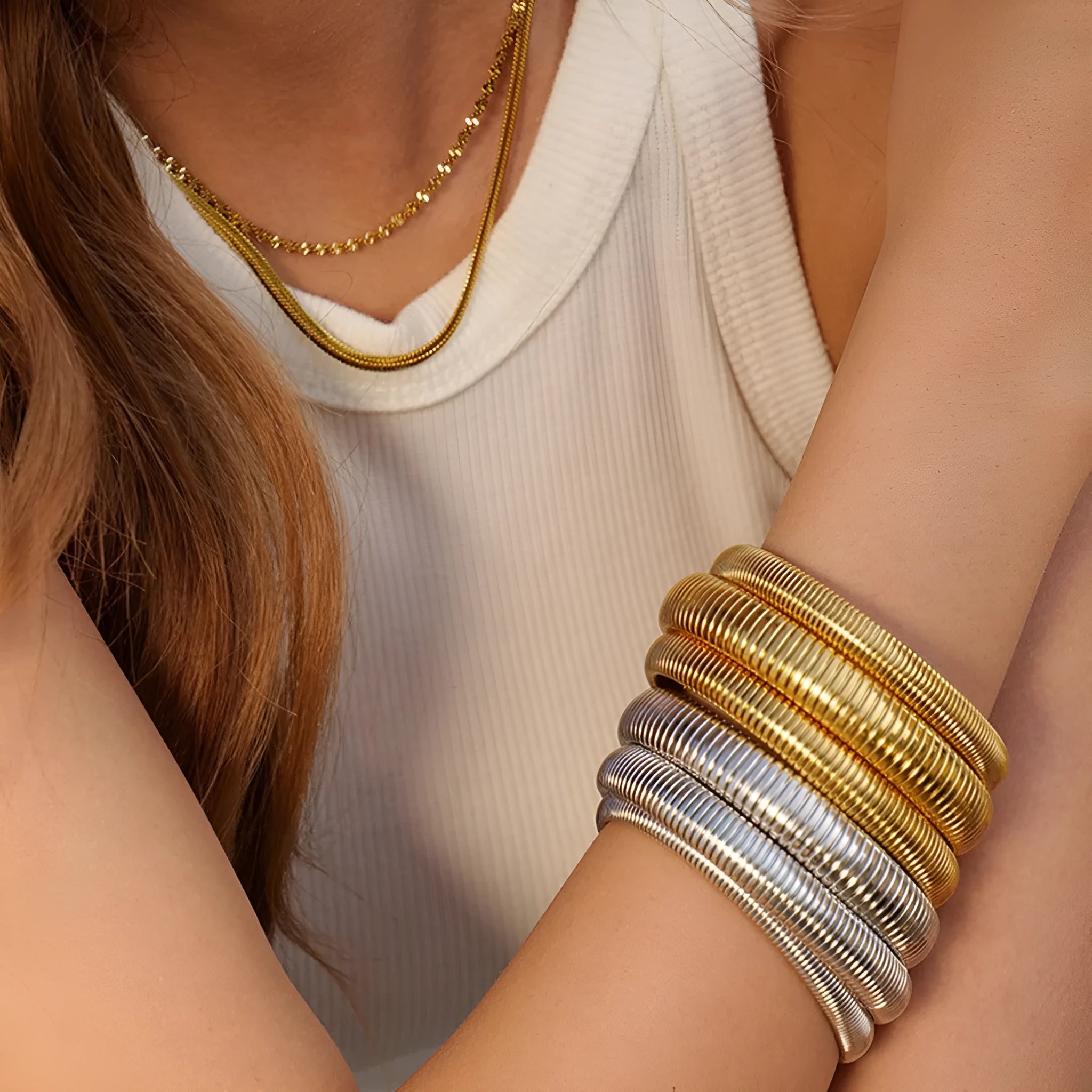 Close-up of a women's titanium steel bracelet with a vertical stripe ring pattern, shown in a gold tone finish on a wrist.