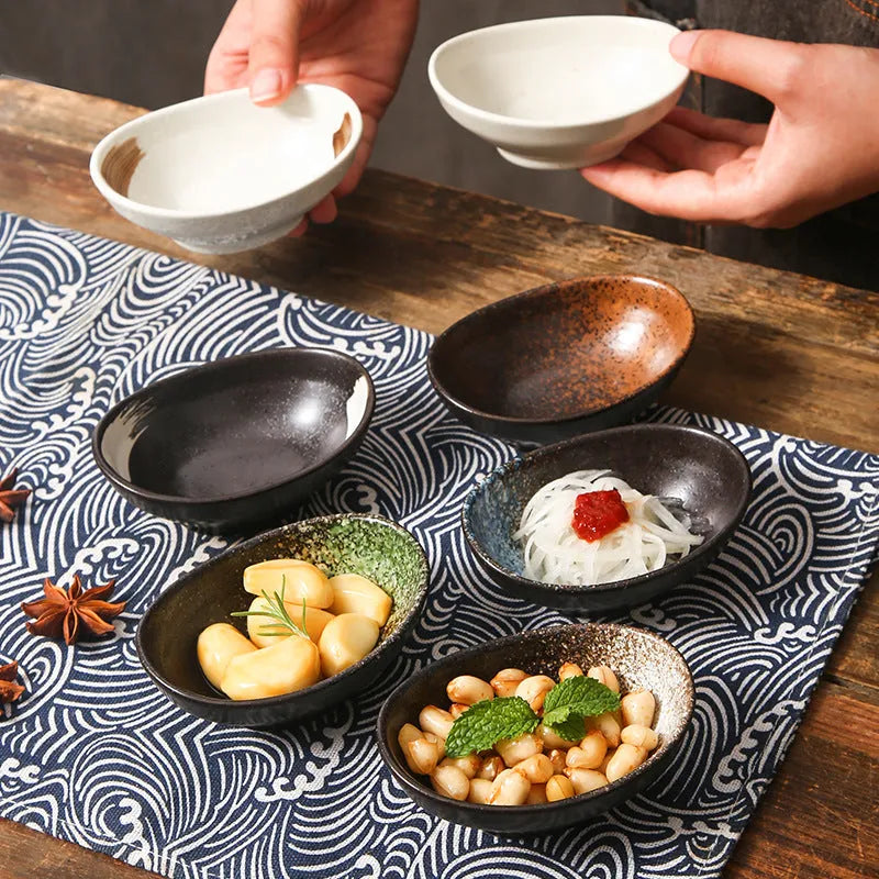 Oval Japanese ceramic dipping bowl with underglaze pattern on a wooden table.