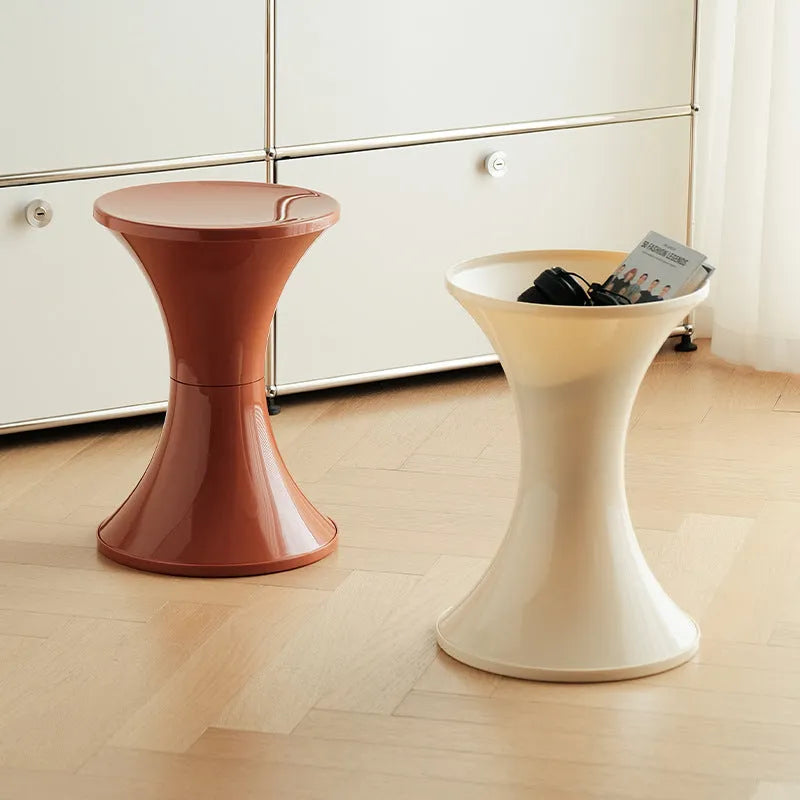 A plastic hourglass-shaped shoe changing stool in green colour on a wooden floor.