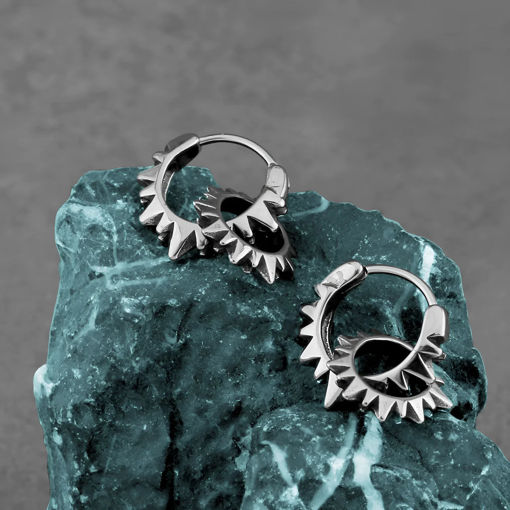 A pair of polished stainless steel round ring earrings in a steel colour on a plain background.
