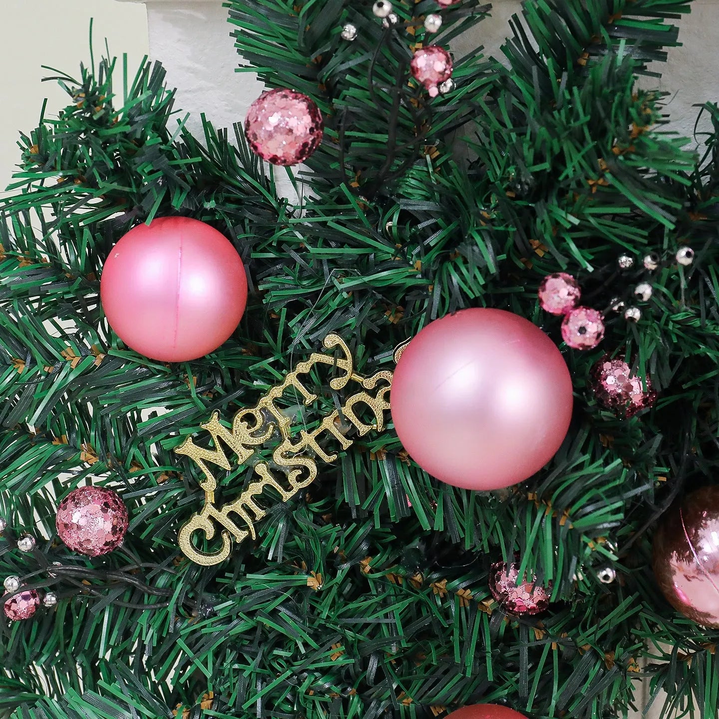 Pink Christmas rattan garland with small fruit details and LED lights draped across doorway