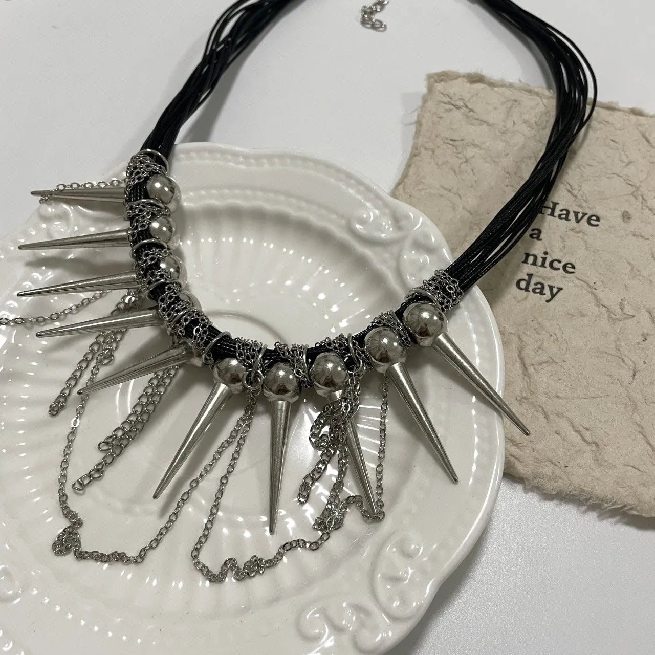 Women's leather necklace with round beads, a winding tassel, and metallic point rivets.