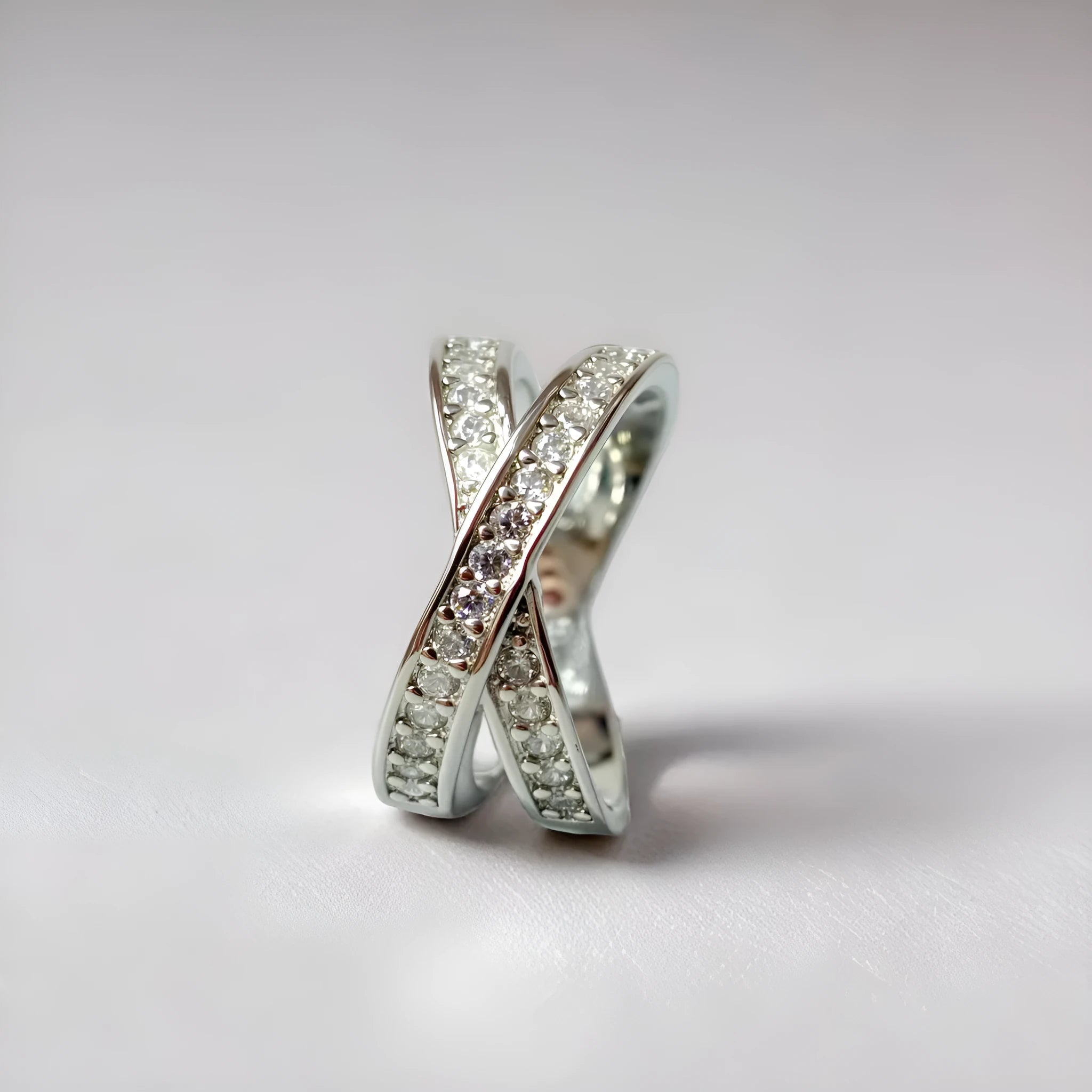 A silver or rose gold plated metal ring with a cross design and micro-inlaid zircon detail.