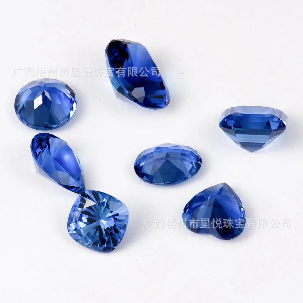 Royal blue loose cultured gemstone in heart, round, and pear shapes on a grey background.
