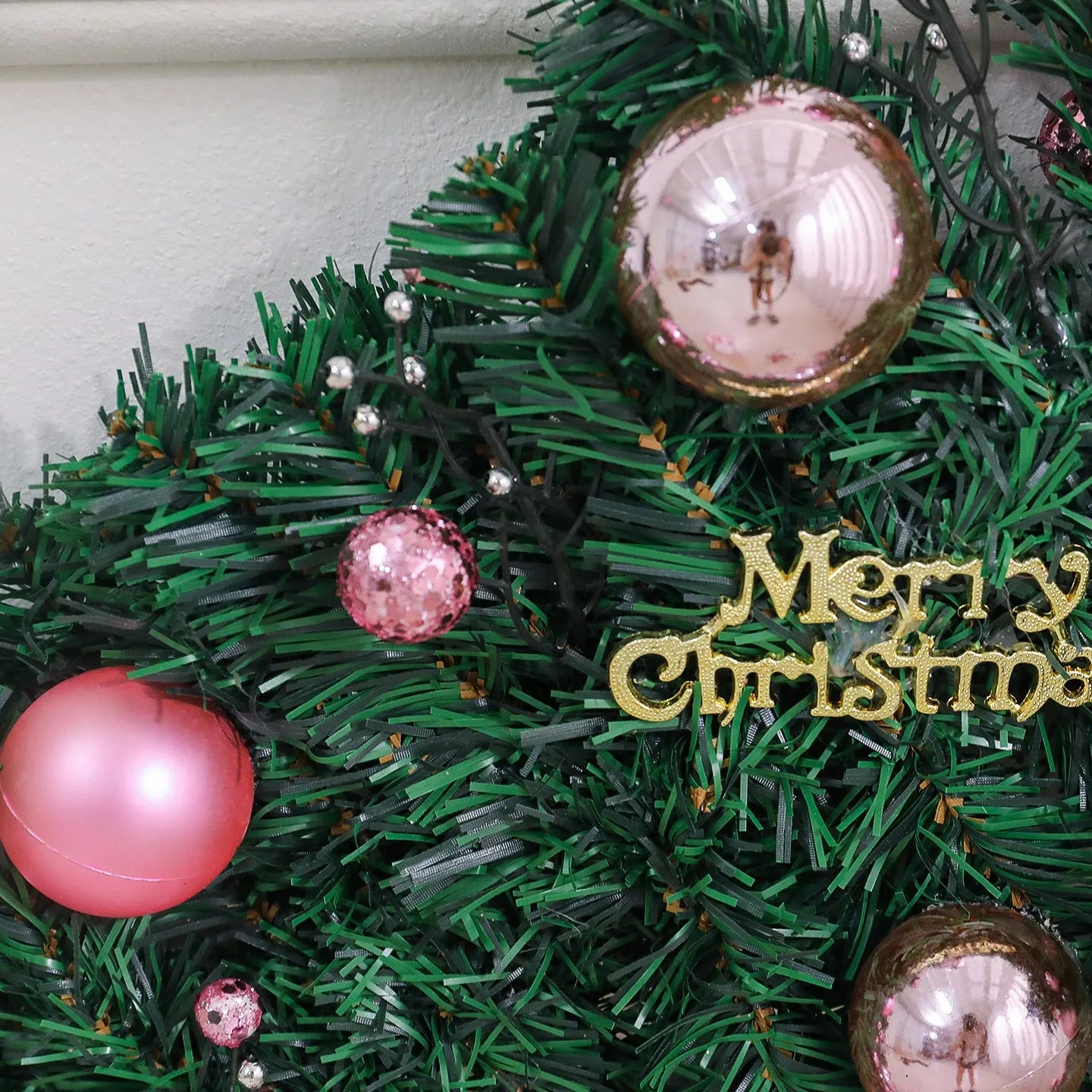 Pink Christmas rattan garland with small fruit details and LED lights draped across doorway