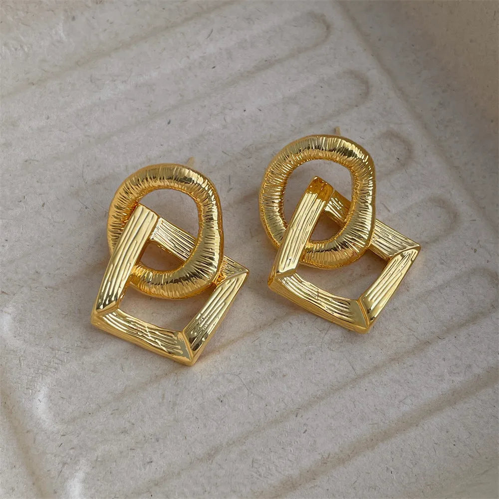 Geometric circle pendant drop earrings in gold or silver tone with a 3.4cm length.