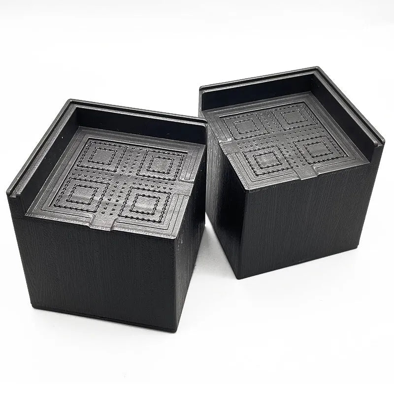 Four black plastic bed foot mats for furniture height adjustment and floor protection
