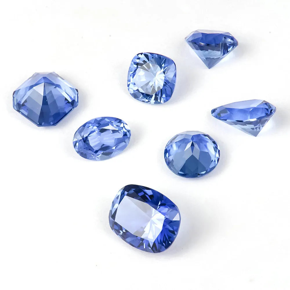Royal blue loose cultured gemstone in heart, round, and pear shapes on a grey background.