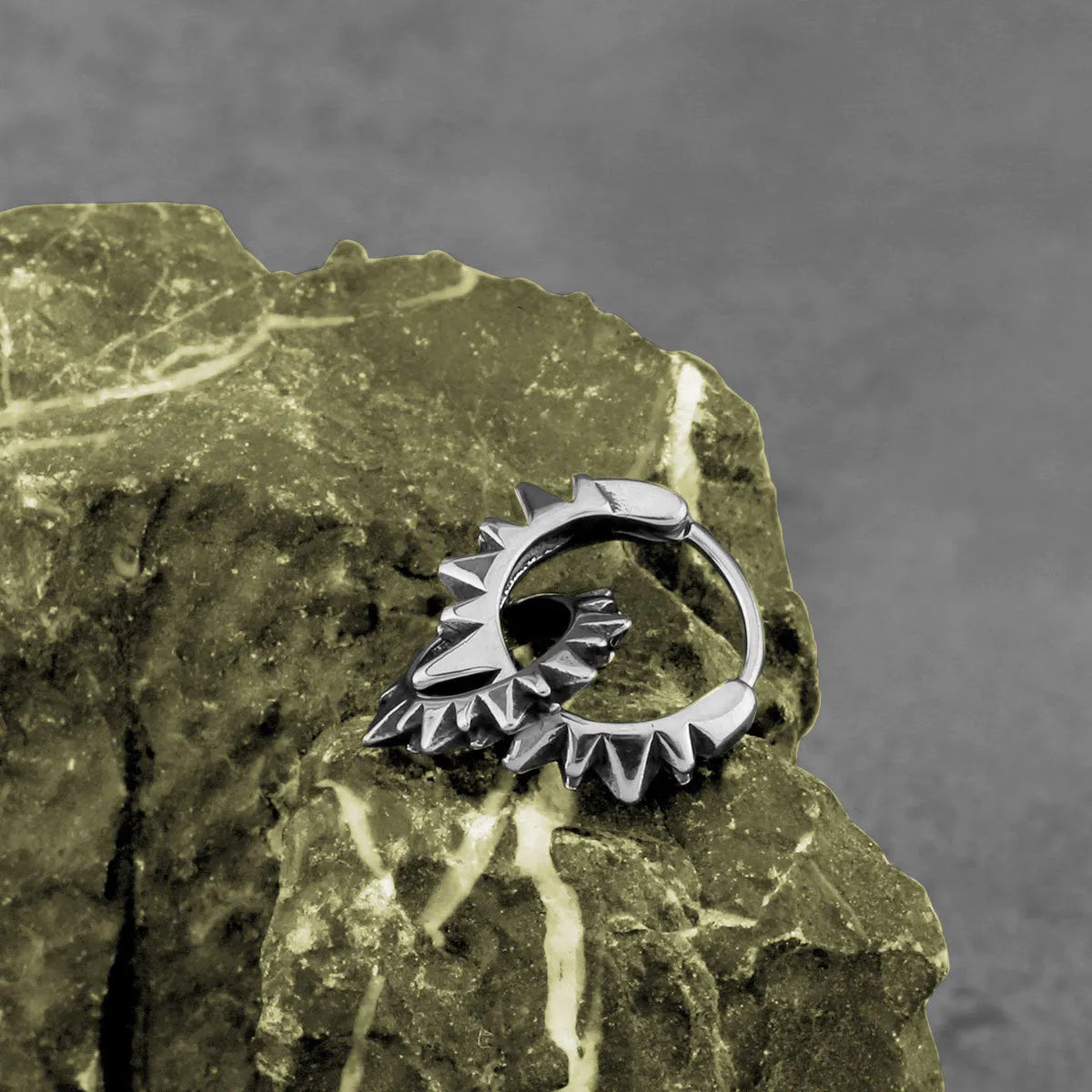 A pair of polished stainless steel round ring earrings in a steel colour on a plain background.