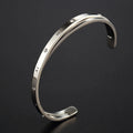 Open-ended stainless steel bracelet with zircon stones and love motif in electroplated gold finish