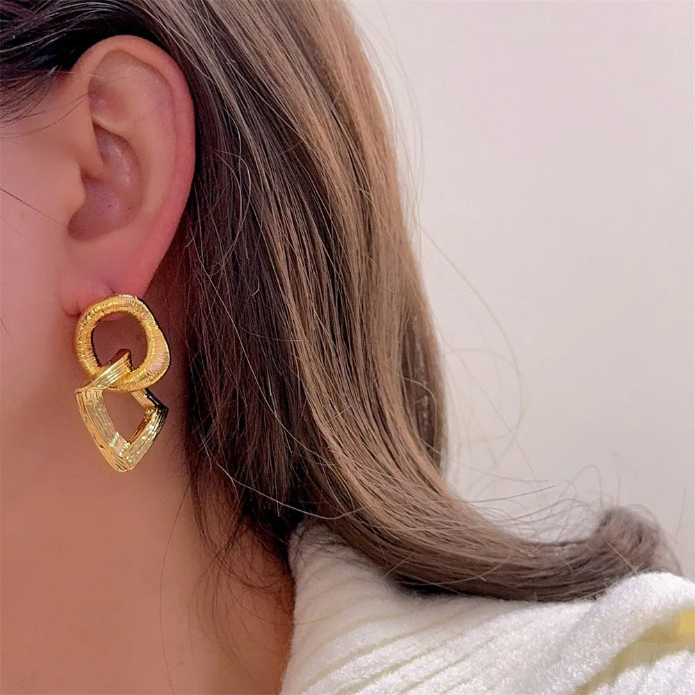 Geometric circle pendant drop earrings in gold or silver tone with a 3.4cm length.