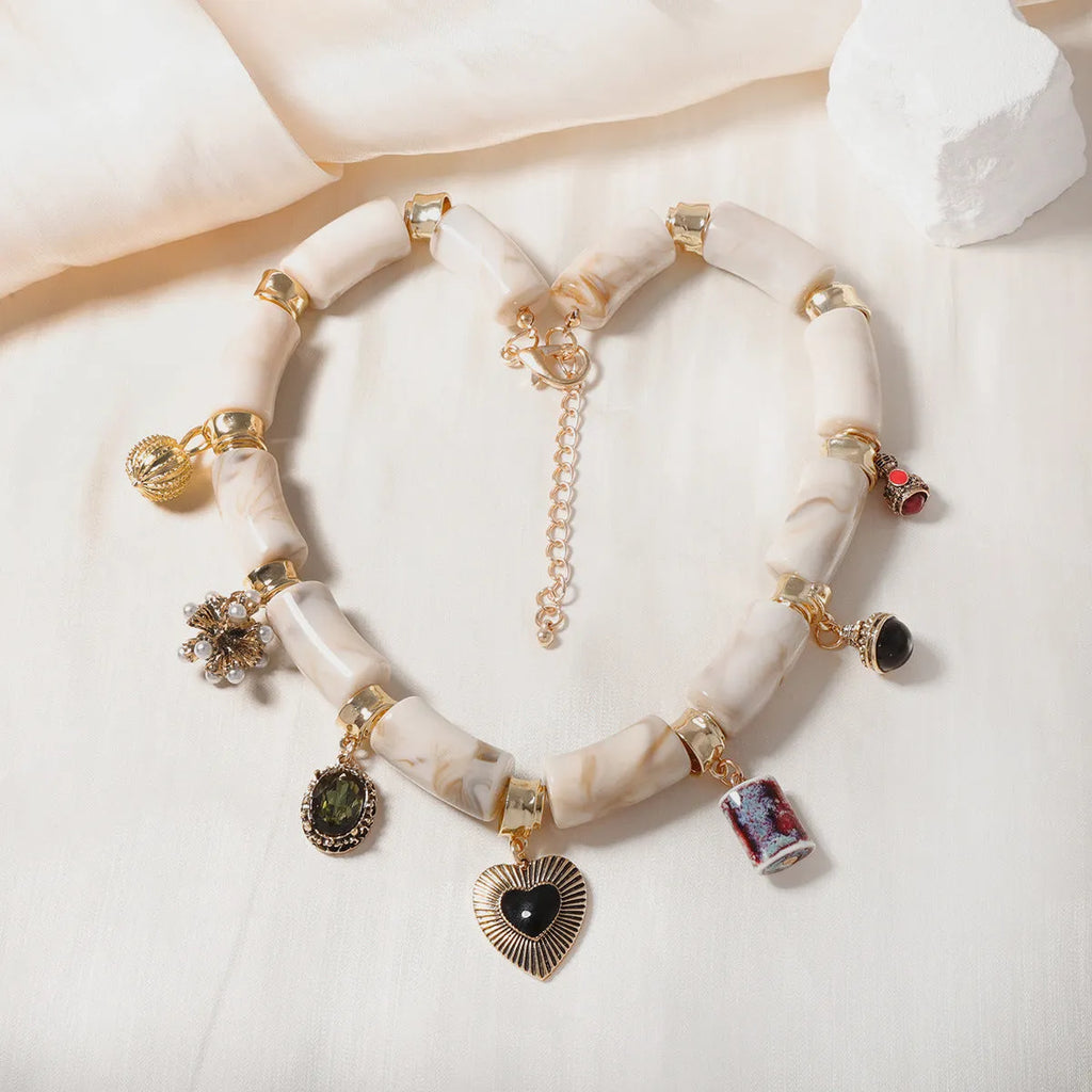 Gold-plated chain necklace with a white heart-shaped resin bamboo pendant.