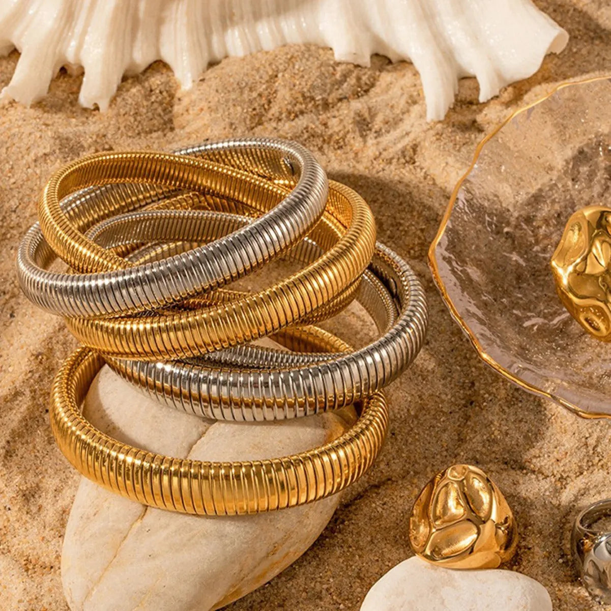 Close-up of a women's titanium steel bracelet with a vertical stripe ring pattern, shown in a gold tone finish on a wrist.