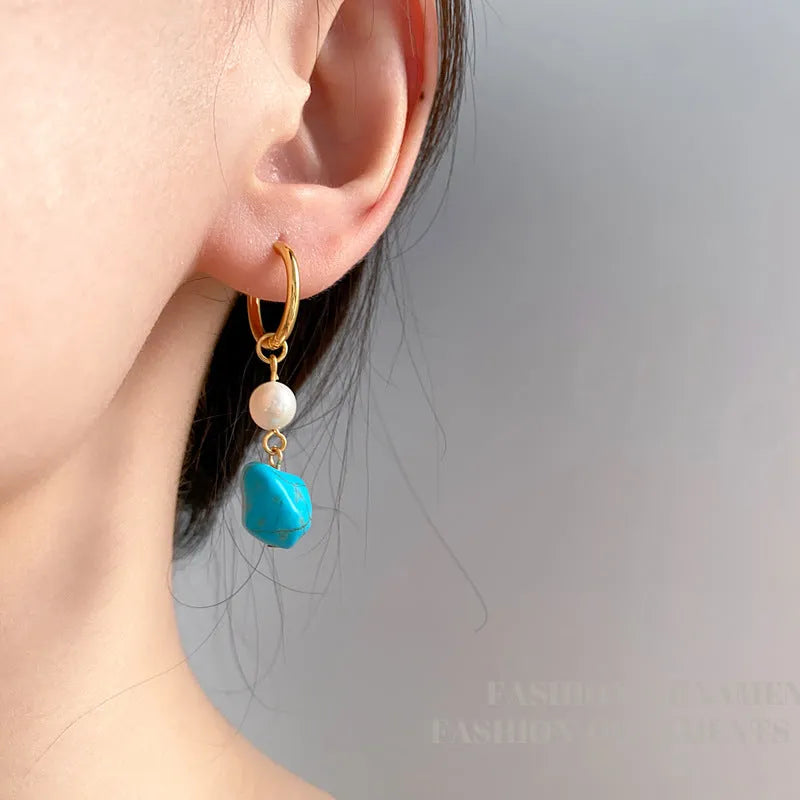 Geometric turquoise and cultured pearl earrings in short stud and long dangle styles on copper settings.