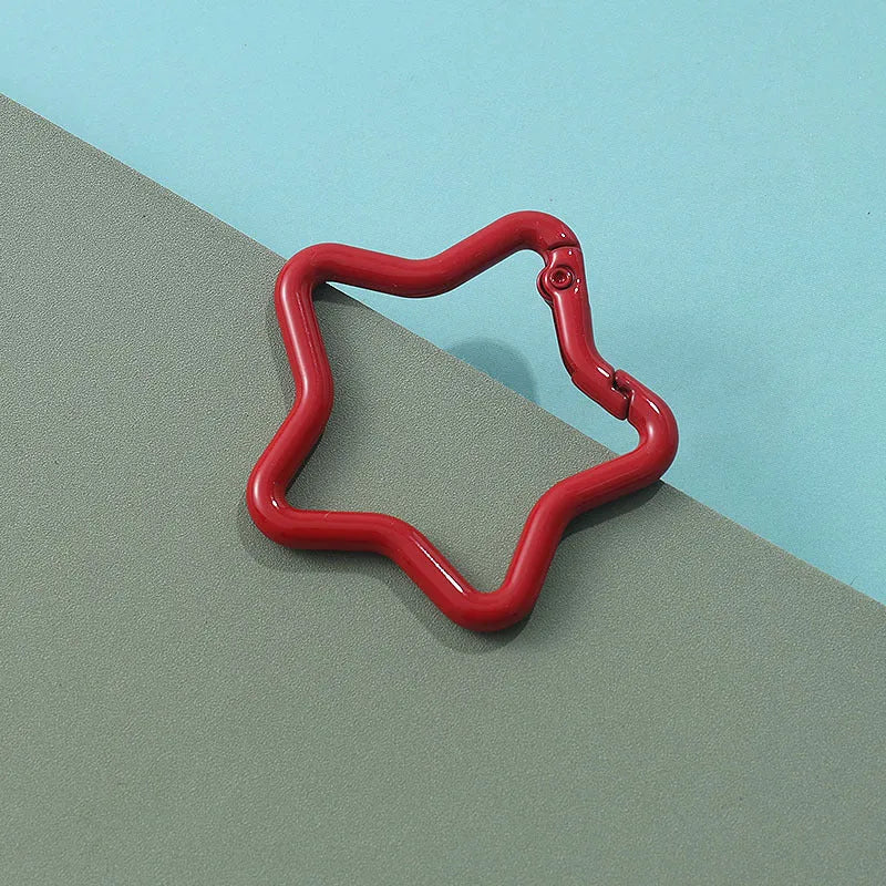 Zinc alloy five-pointed star keychain in light pink colour on a white background.