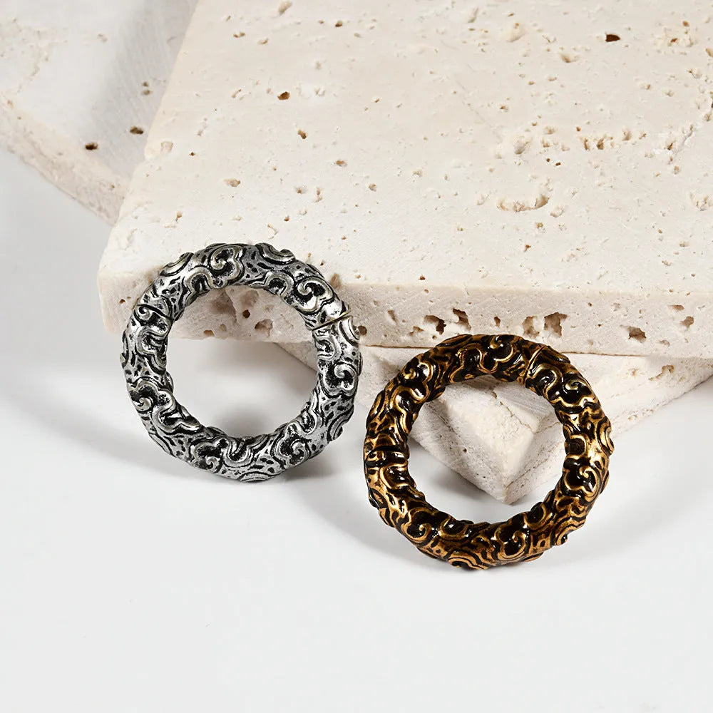 A pair of silver totem pattern stainless steel fashion earrings on a white background.