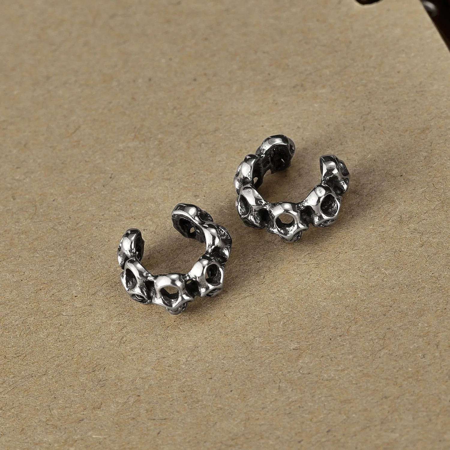 Stainless steel hollow skull ear clips with geometric design and metallic finish