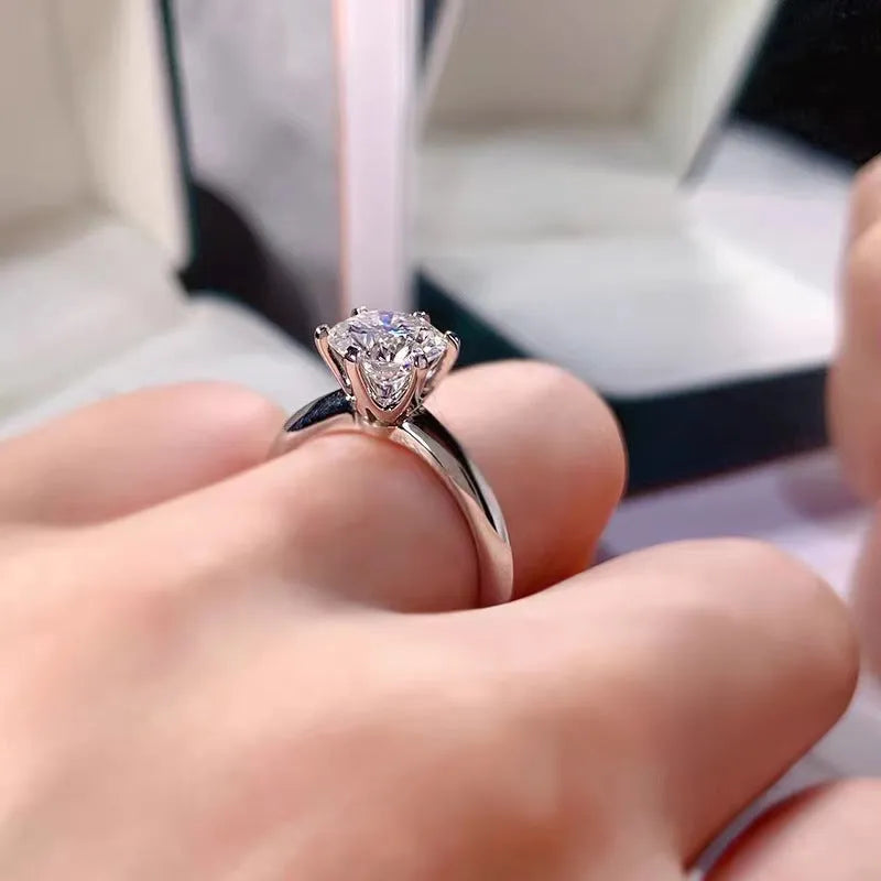 White gold plated geometric women's ring with a six-claw zircon setting, shown on a hand.