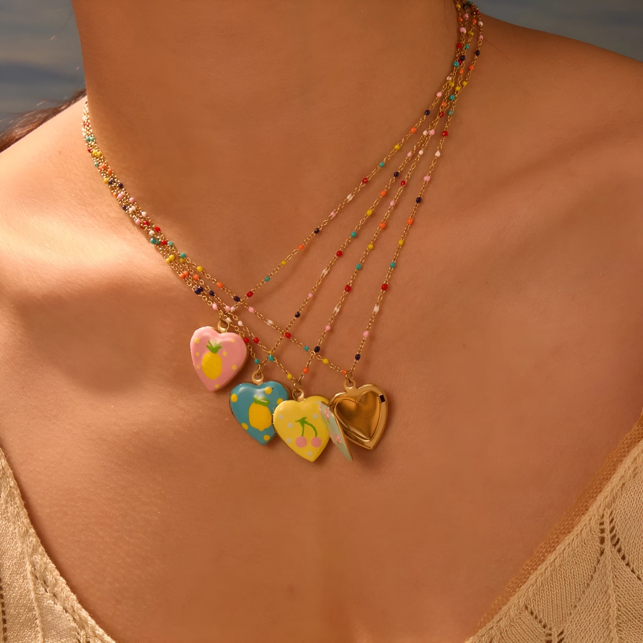 Gold-plated heart-shaped fruit pendant necklace on a stainless steel chain, showing grape design detail.