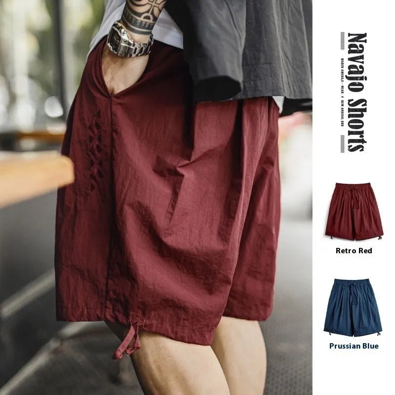 Prussian blue men's loose fit nylon shorts with embroidery on a plain background.