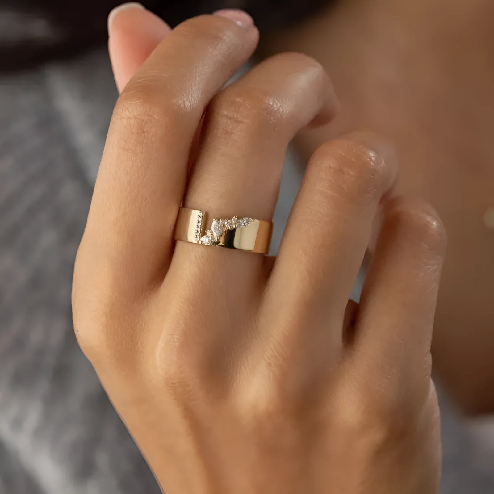 Gold electroplated women's ring with a shining zircon stone, shown on a finger.