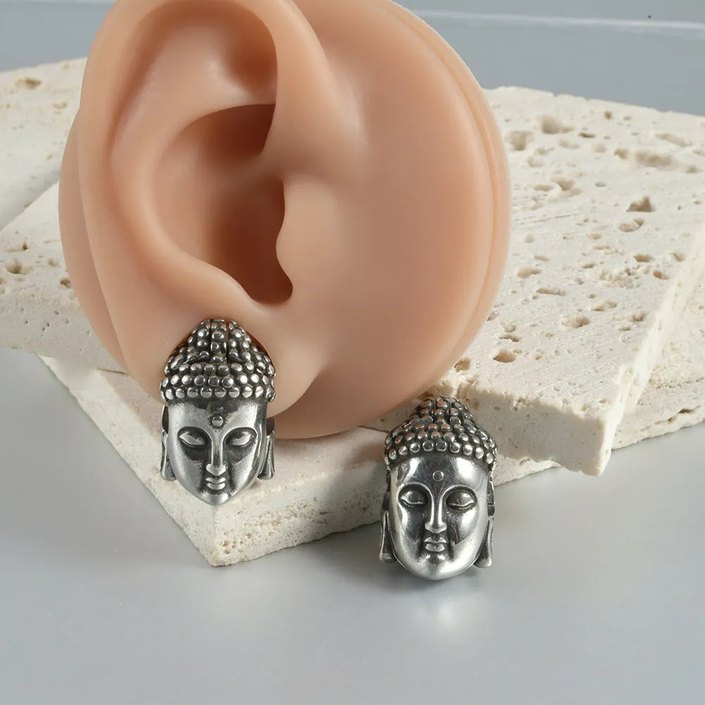 Geometric stainless steel earrings combining hollow skull and Buddha motifs with electroplated finish