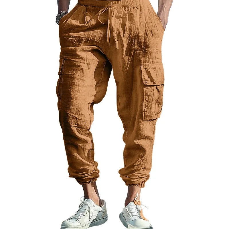 Man wearing loose-fit linen casual trousers with ankle-tied cuffs and multiple pockets in a solid colour.