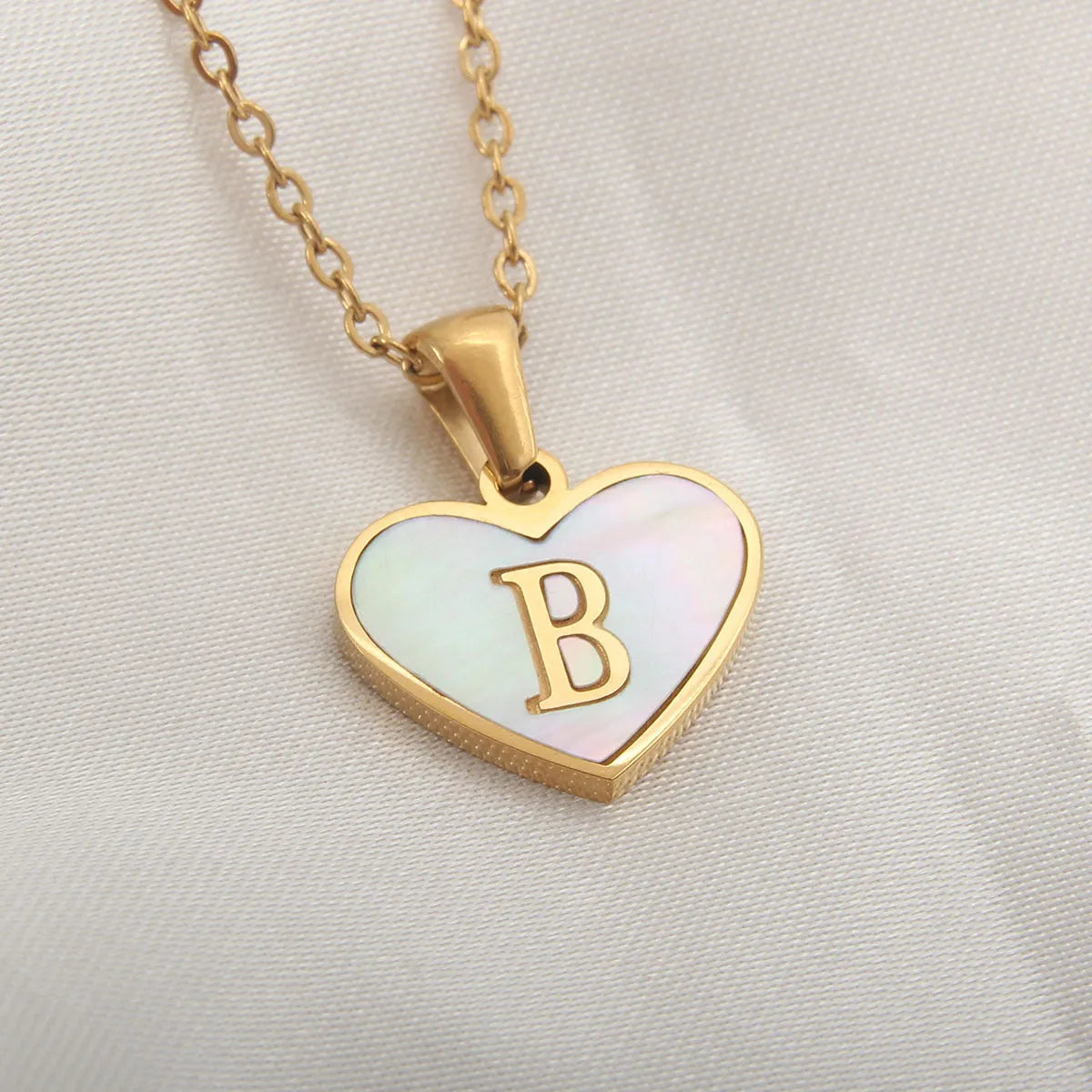 Gold heart necklace with white shell detail and personalised initial letter on adjustable chain