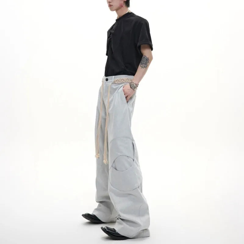 Men's dark blue straight-leg cotton jeans with 3D cutting, belt stitching, and decorative pocket tassels.