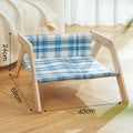 Elevated wooden frame cat bed with soft blue cloth cushion for indoor cats.