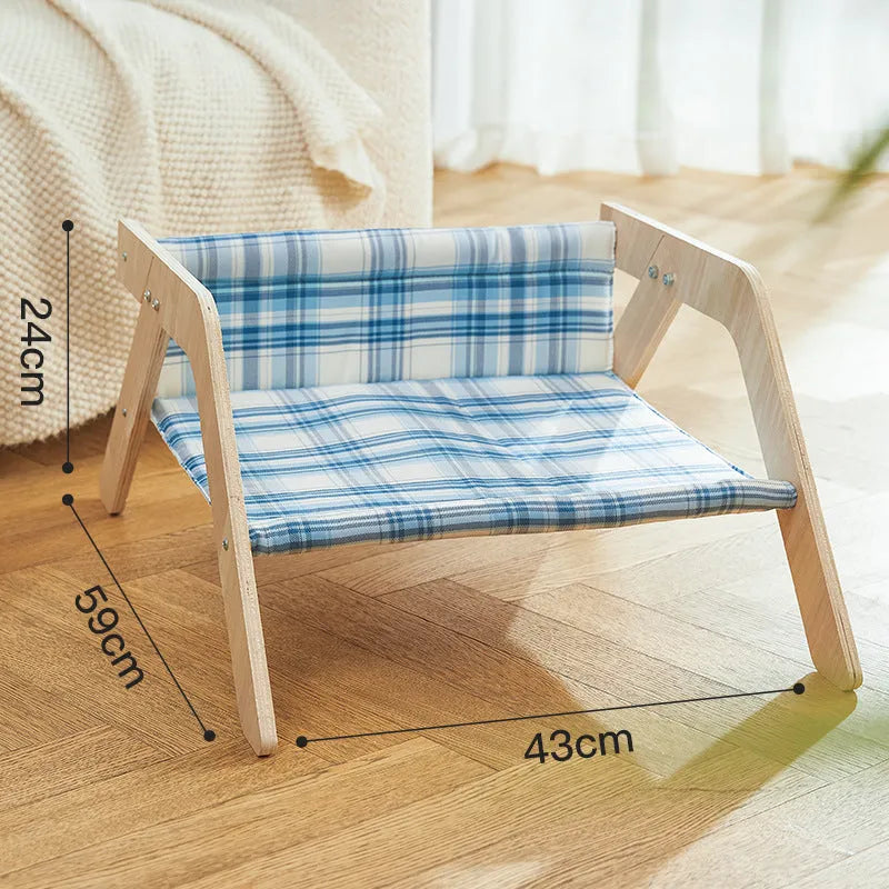 Elevated wooden frame cat bed with soft blue cloth cushion for indoor cats.