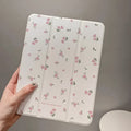 Transparent tri-fold iPad case with floral cartoon pattern, shown in standing position with magnetic closure