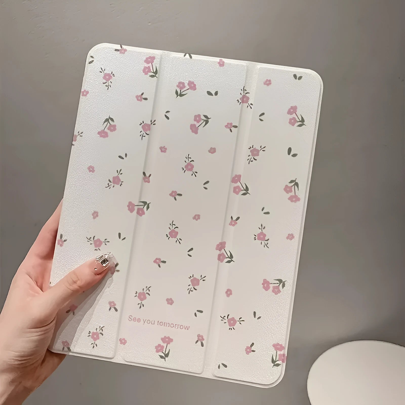 Transparent tri-fold iPad case with floral cartoon pattern, shown in standing position with magnetic closure