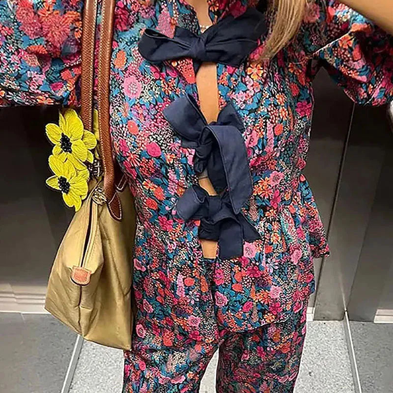 Women's floral print trouser suit set featuring a puff sleeve top with tie-neck and matching trousers.