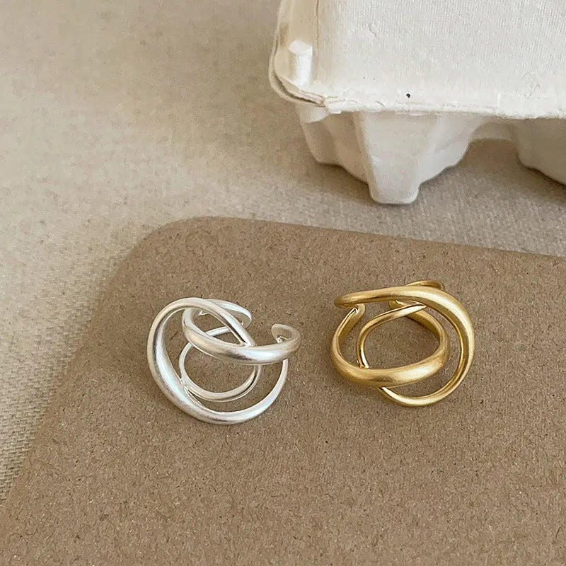 Geometric interlaced open ring with a matte metal finish in gold tone plating.
